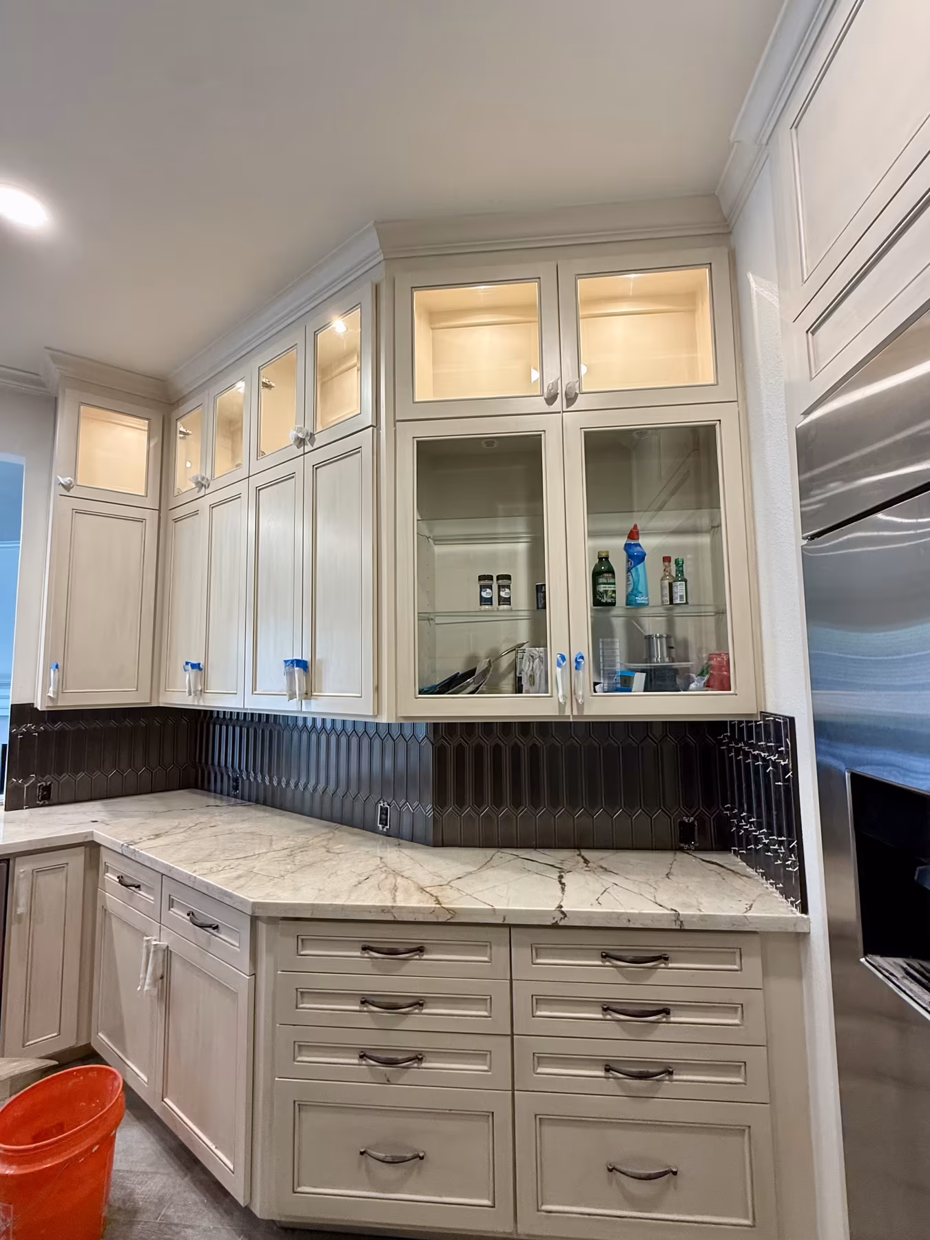 Glass-front display cabinetry in a butler's pantry with marble counters
