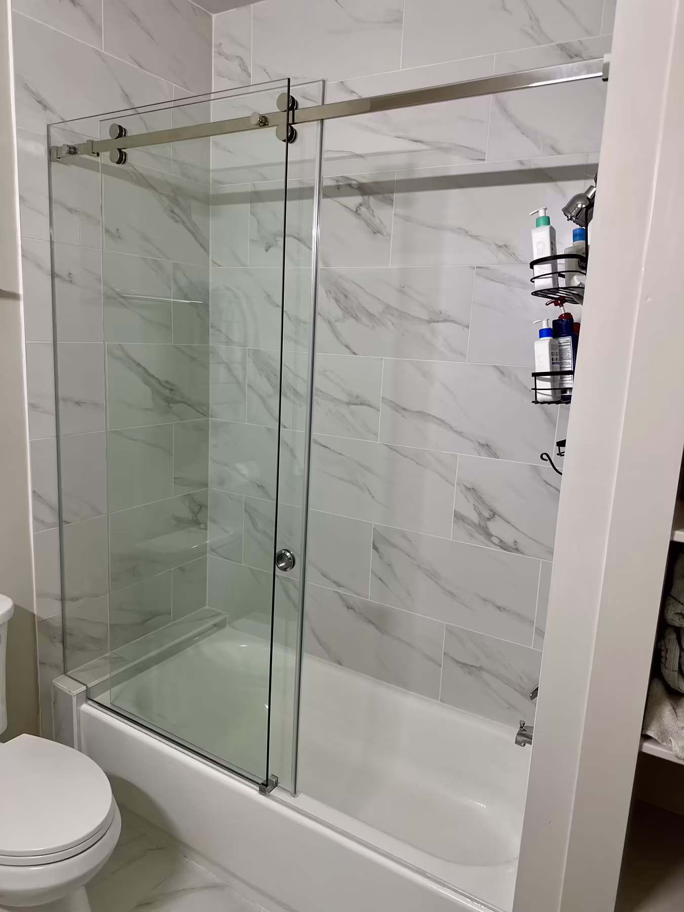 Sliding glass shower over tub with marble subway tile